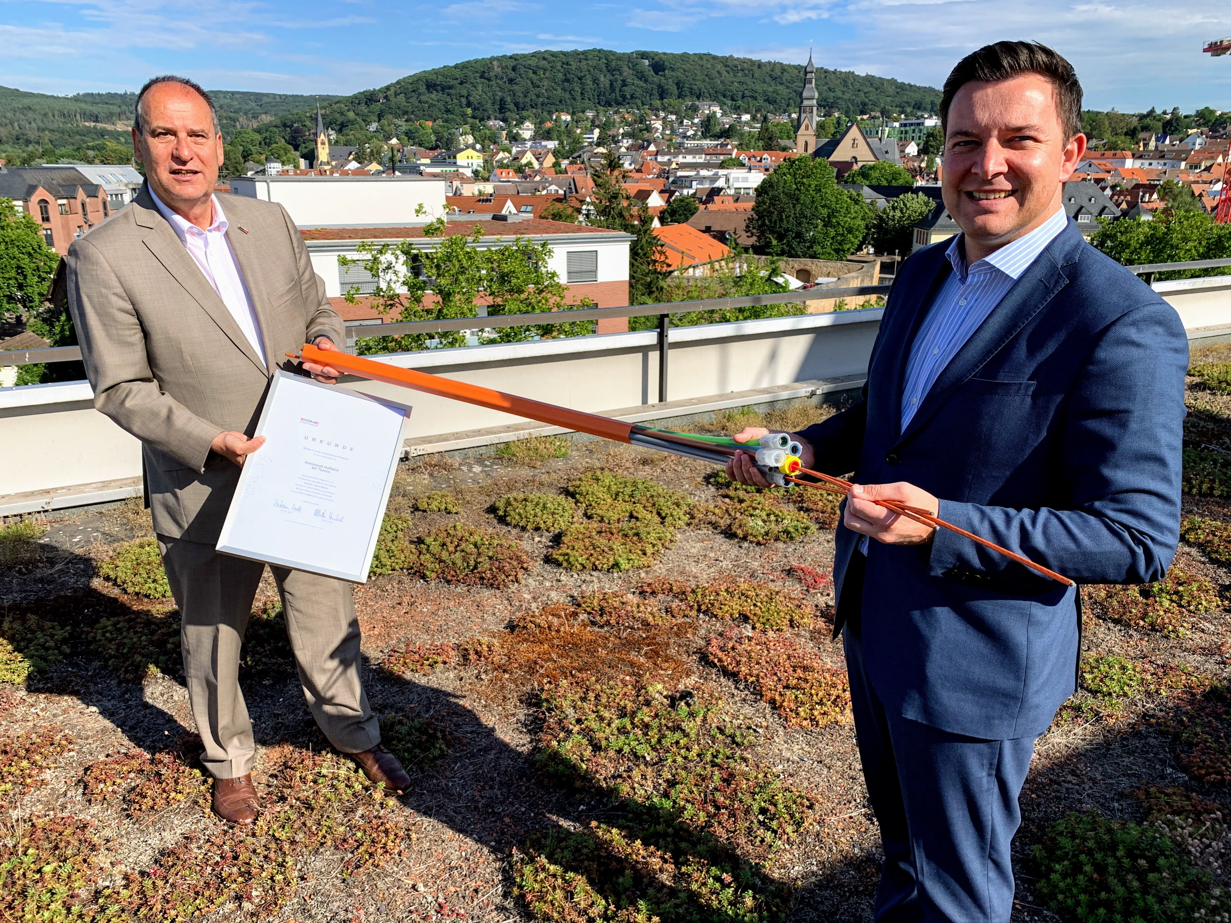 Bertam Huke und Christian Vogt präsentieren ein Glasfaser-Kabel und ein Dokument.