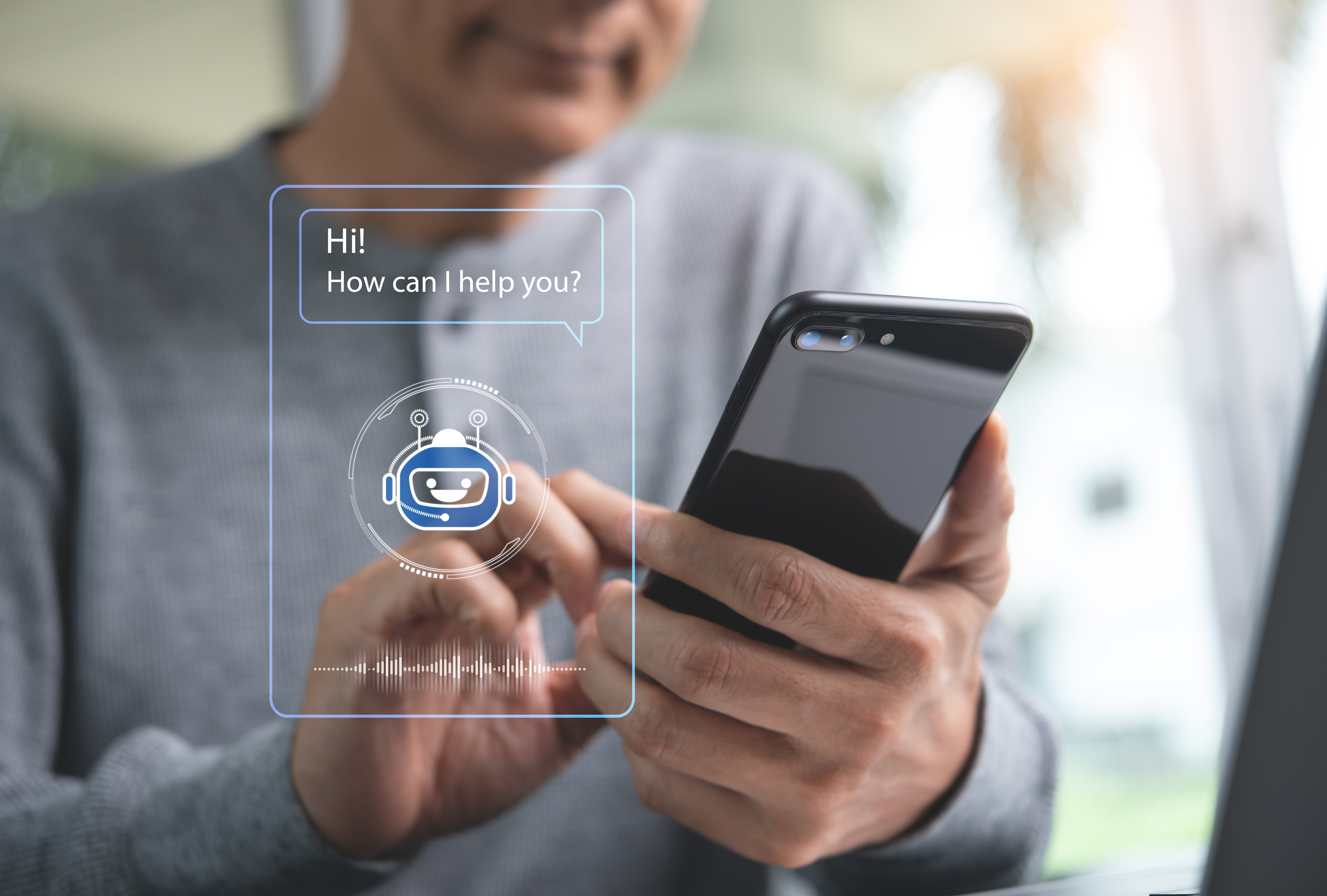 Chatbot assistant, Ai Artificial Intelligence Ausschnitt eines Programms; im Hintergrund hält ein Mann ein Smartphone.