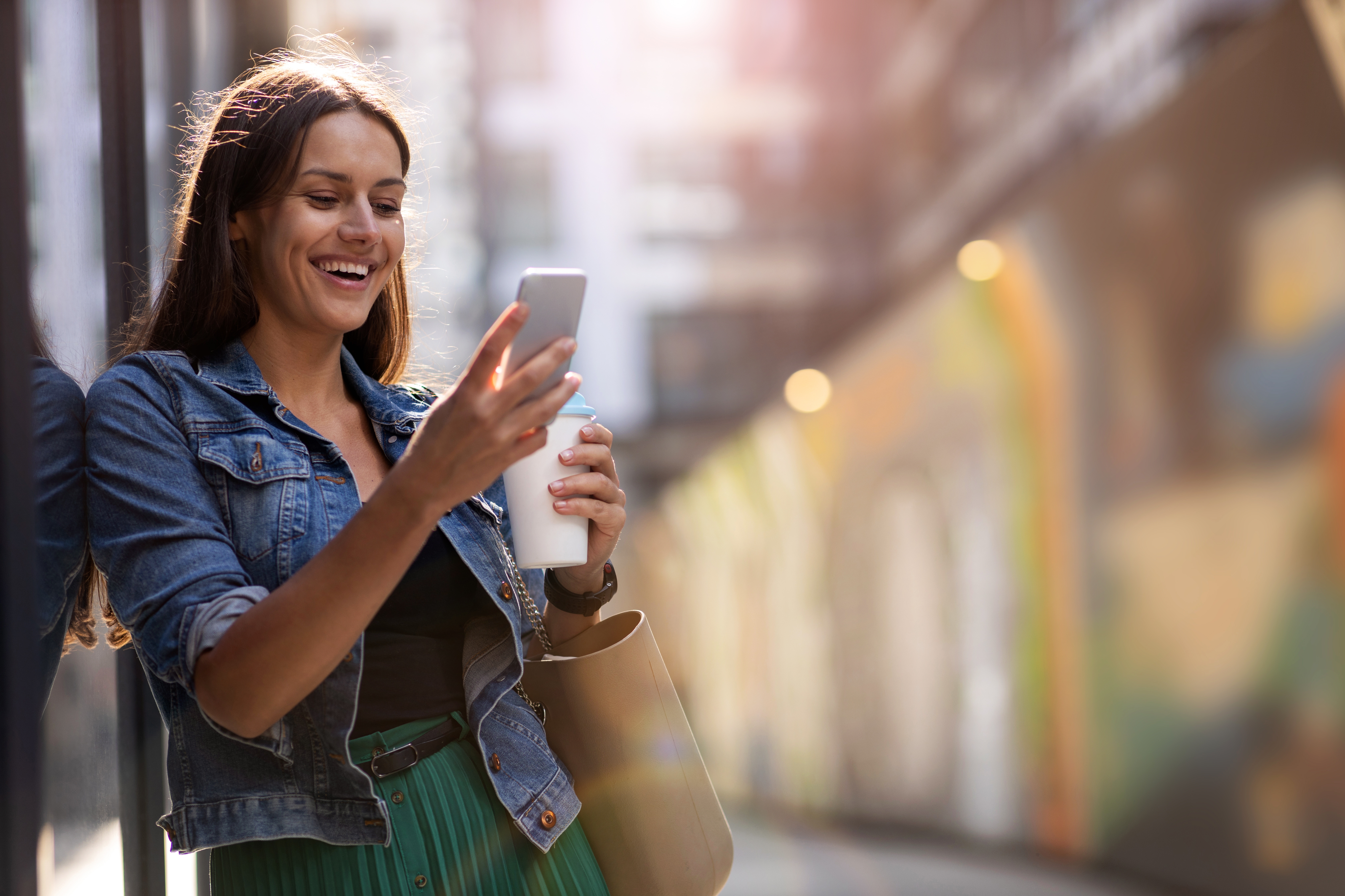 Young woman with smartphone in an urban city area Lächelnde Frau hält ein Smartphone.