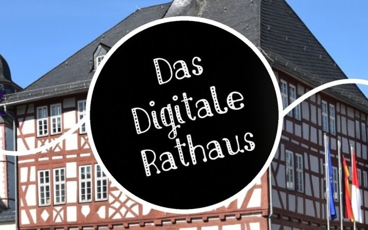 Schriftzug; mit einem Rathausgebäude im Hintergrund.