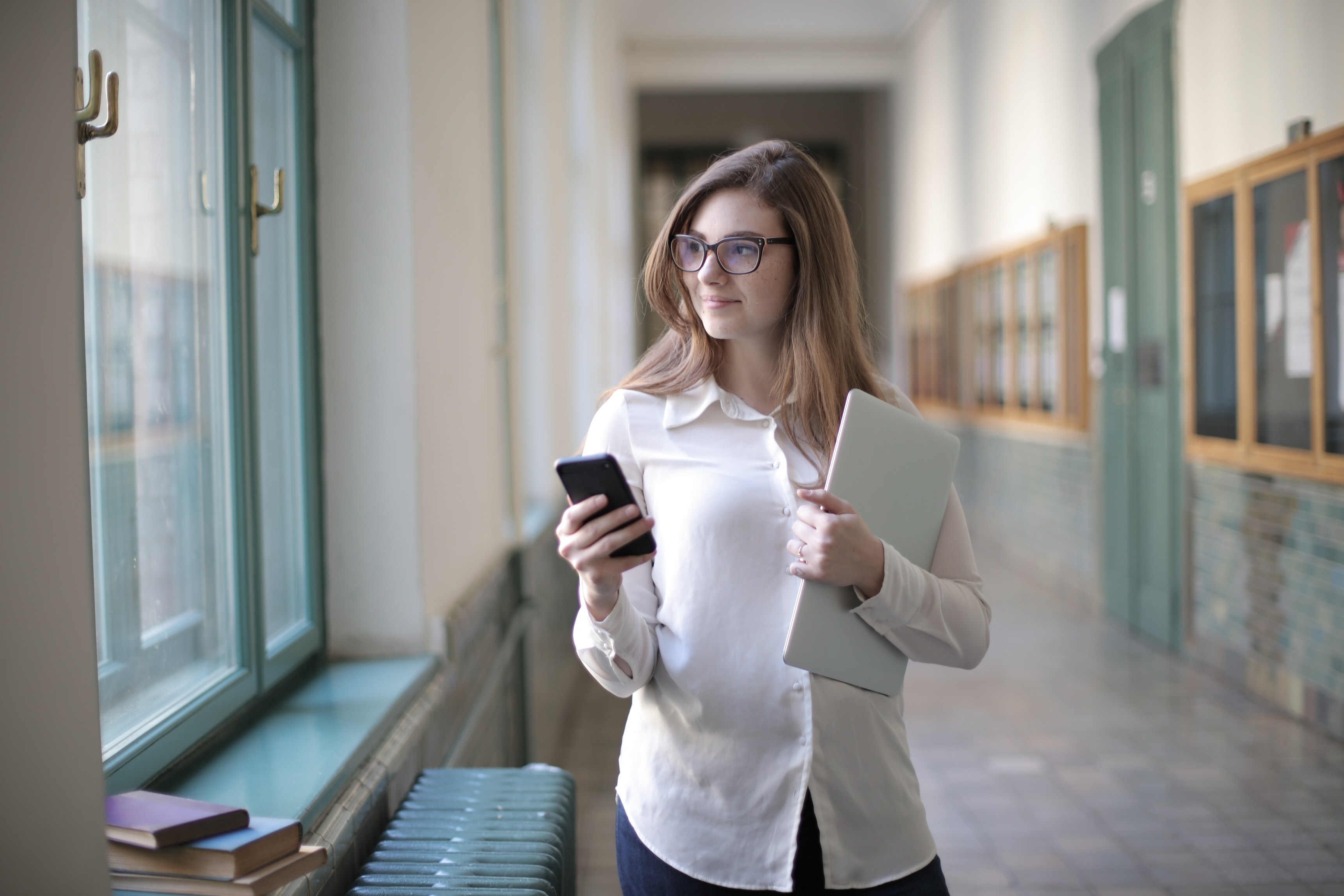 Frau hält ein Smartphone und einen Laptop in ihren Händen.