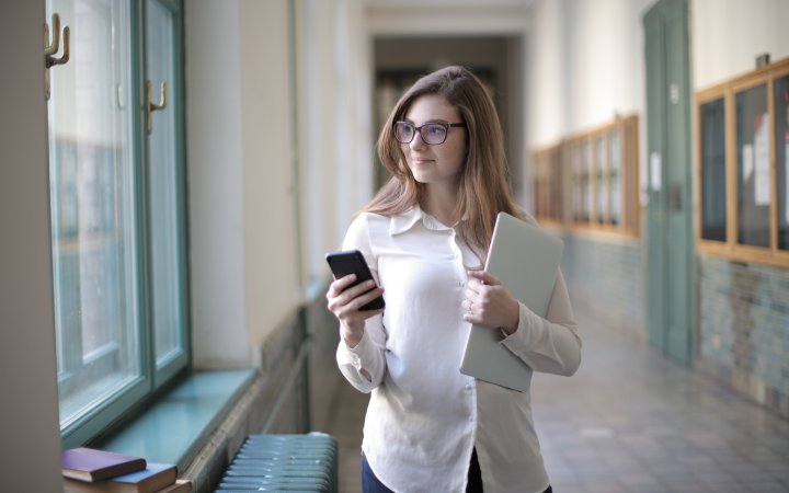 Frau hält ein Smartphone und einen Laptop in ihren Händen.