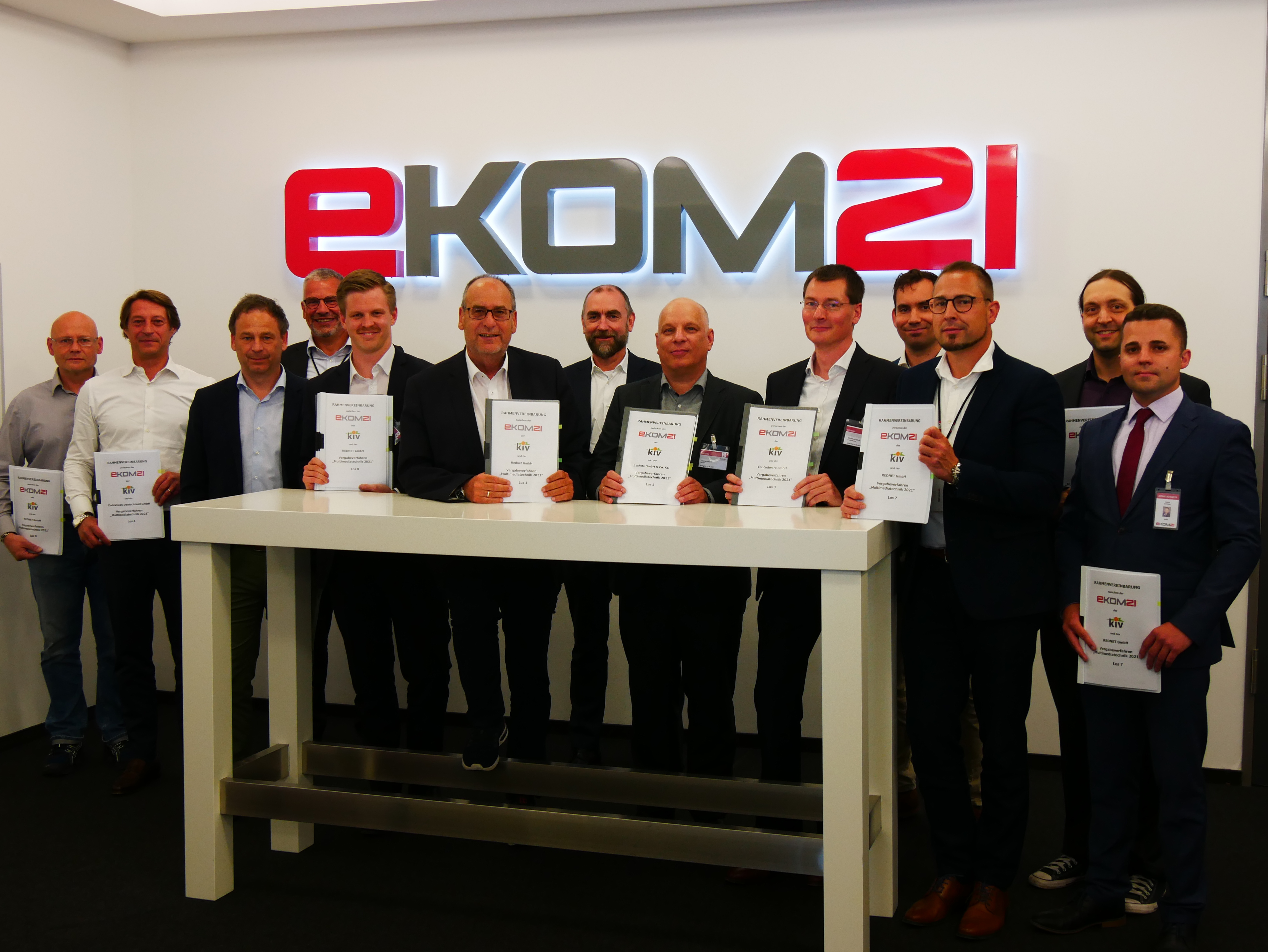 Gruppe von Personen in Räumlichkeiten der ekom21 präsentieren unterzeichnete Verträge.