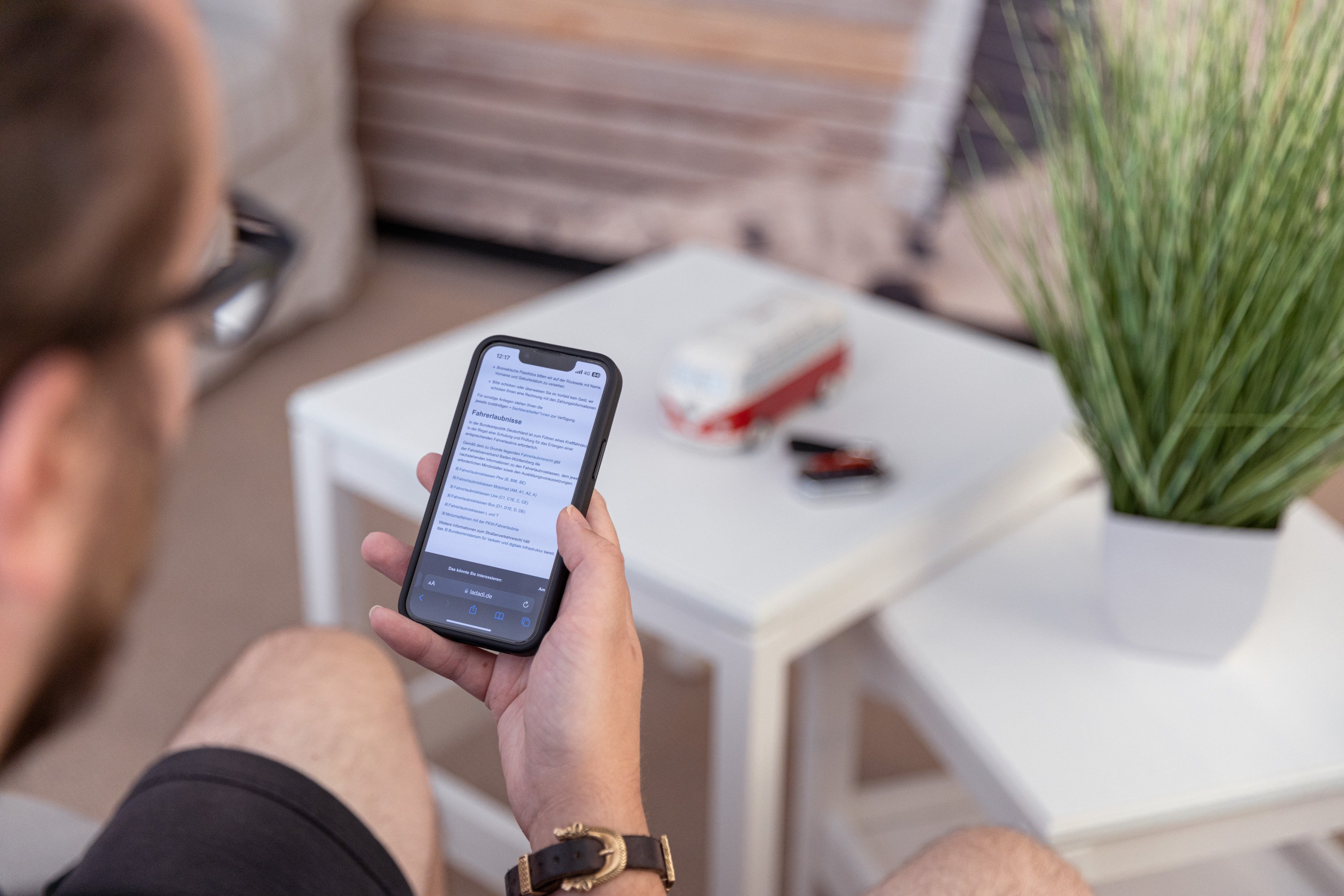 Junger Mann auf Couch schaut auf Smartphone.