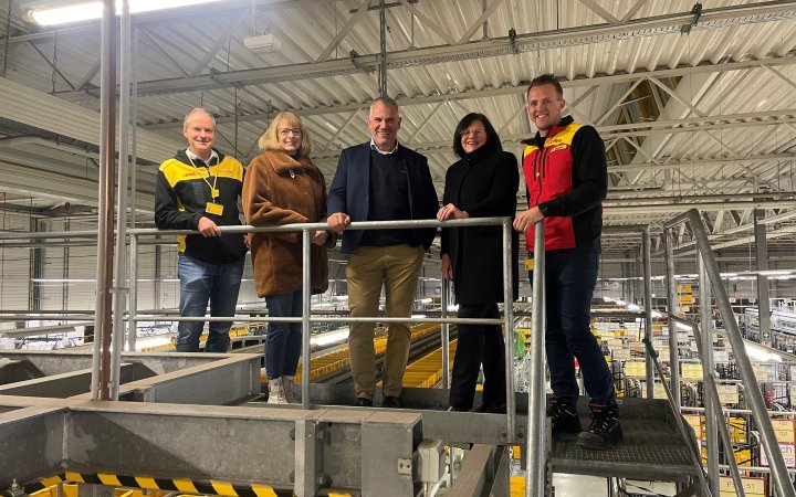 Matthias Drexelius mit vier Personen in einem Logistikgebäude der deutschen Post