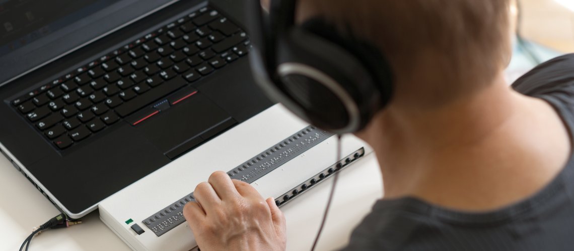 Blind person working on computer with braille display and screen reader Person bedient eine Braillezeile