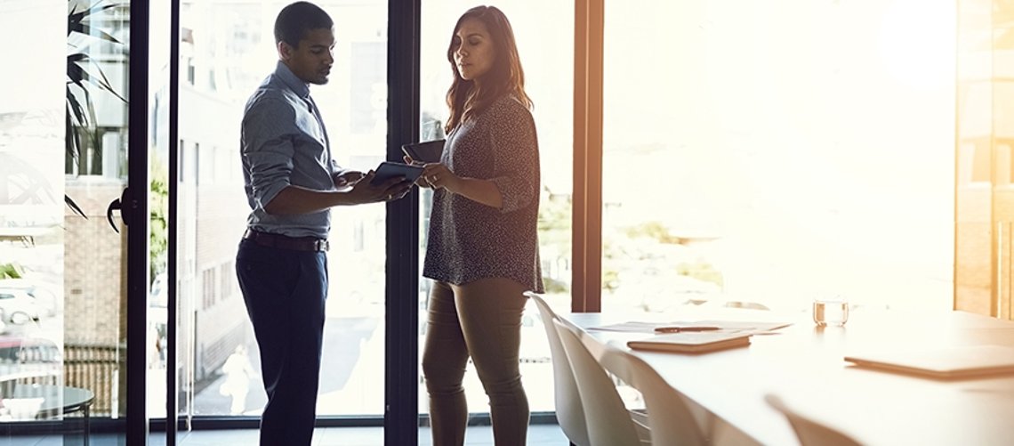 Zwei Personen vor Fenster mit Handy und Tablet in den Händen