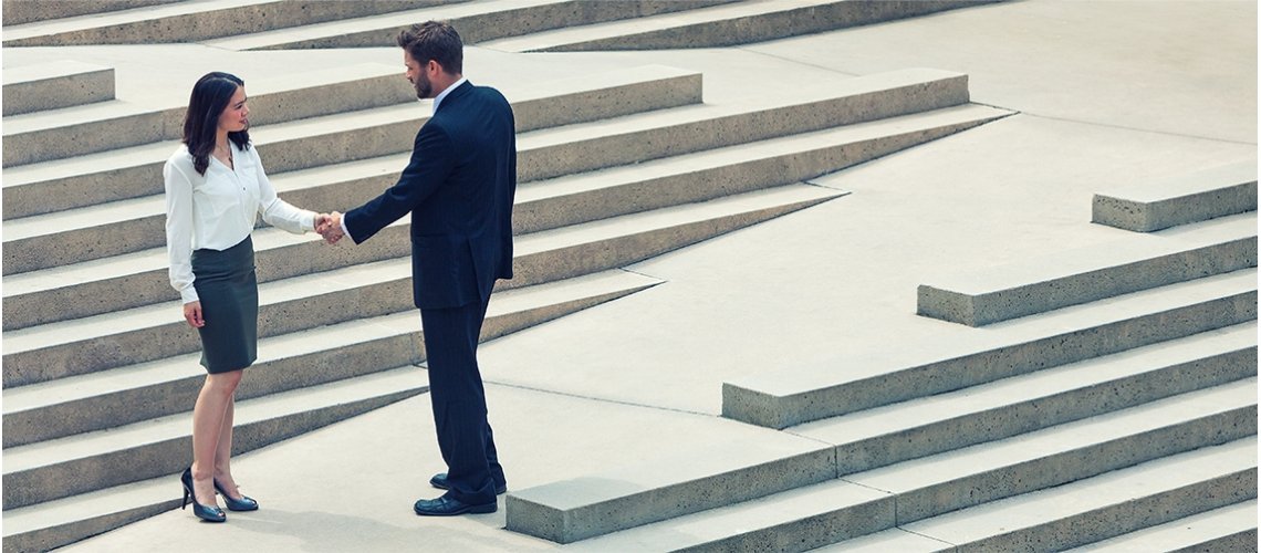 Frau und Mann geben sich die Hand; im Hintergrund Treppen
