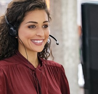 Eine Frau mit Headset auf dem Kopf vor einem Bildschirm