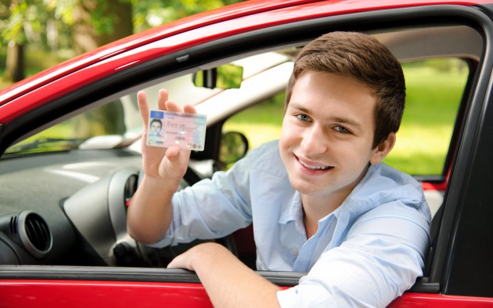 Sitzender Mann in Auto präsentiert einen Führerschein.