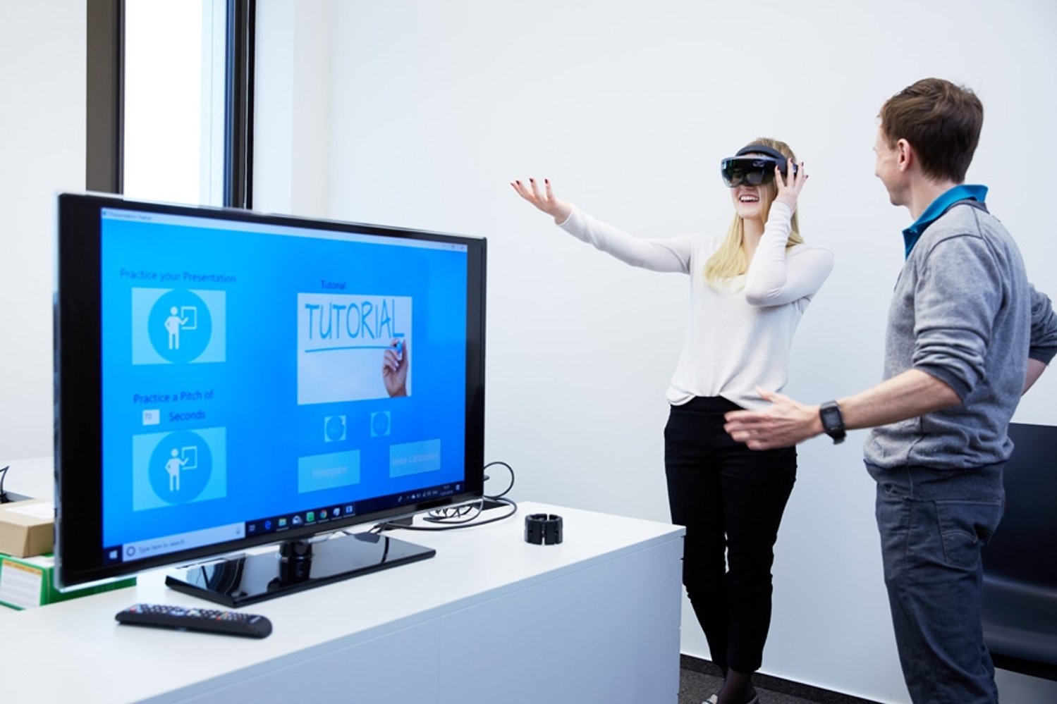 Zwei Personen vor einem Bildschirm; eine Person trägt eine virtuelle Brille.