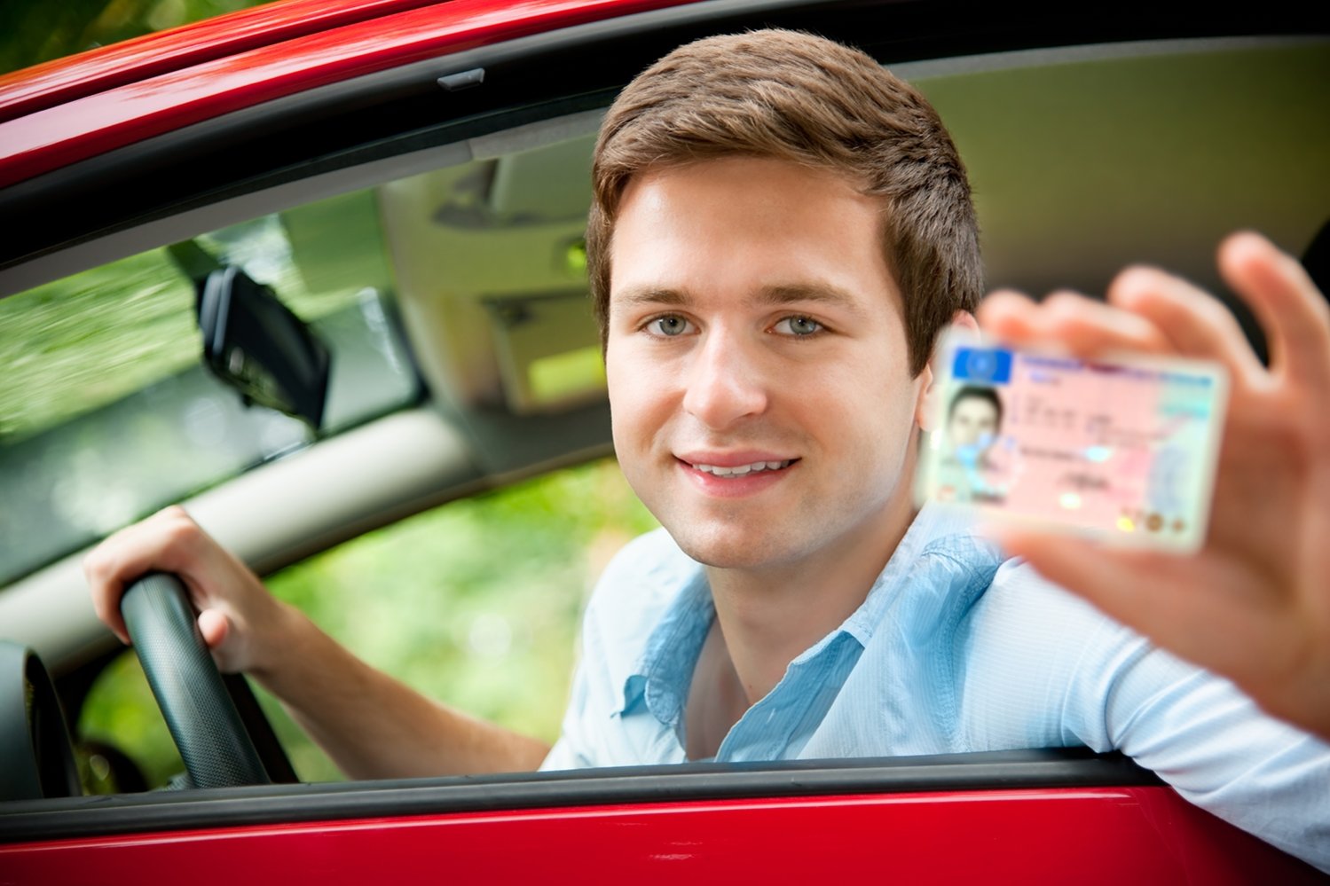 drivers license Mann sitzt in einem Auto und präsentiert seinen Führerschein.