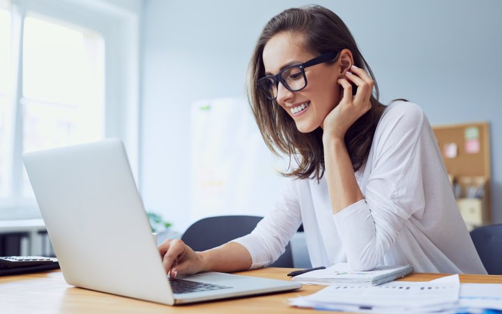 Portrait of beautiful cheerful young businesswoman working on laptop and laughing in home office