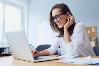 Portrait of beautiful cheerful young businesswoman working on laptop and laughing in home office Portrait of beautiful cheerful young businesswoman working on laptop and laughing in home office