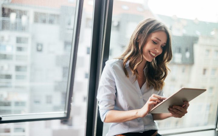 Lächelnde Frau hält ein Tablet in der Hand.