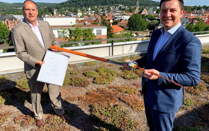 Bertam Huke und Christian Vogt präsentieren ein Glasfaser-Kabel und ein Dokument.