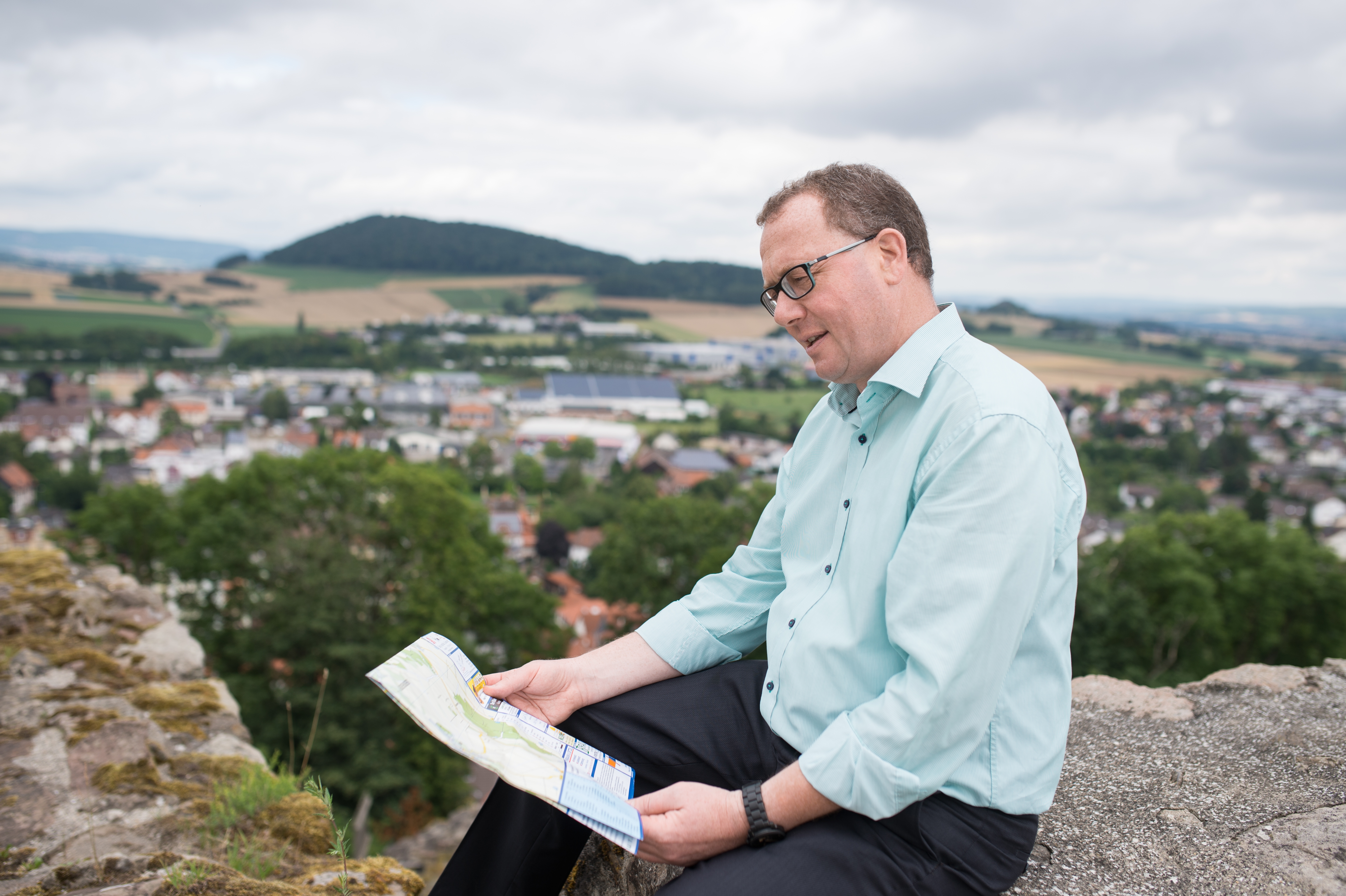 Frank Börner hält eine Landkarte; auf die er blickt.