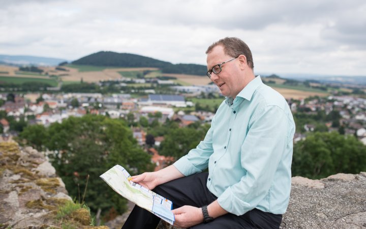 Frank Börner hält eine Landkarte; auf die er blickt.