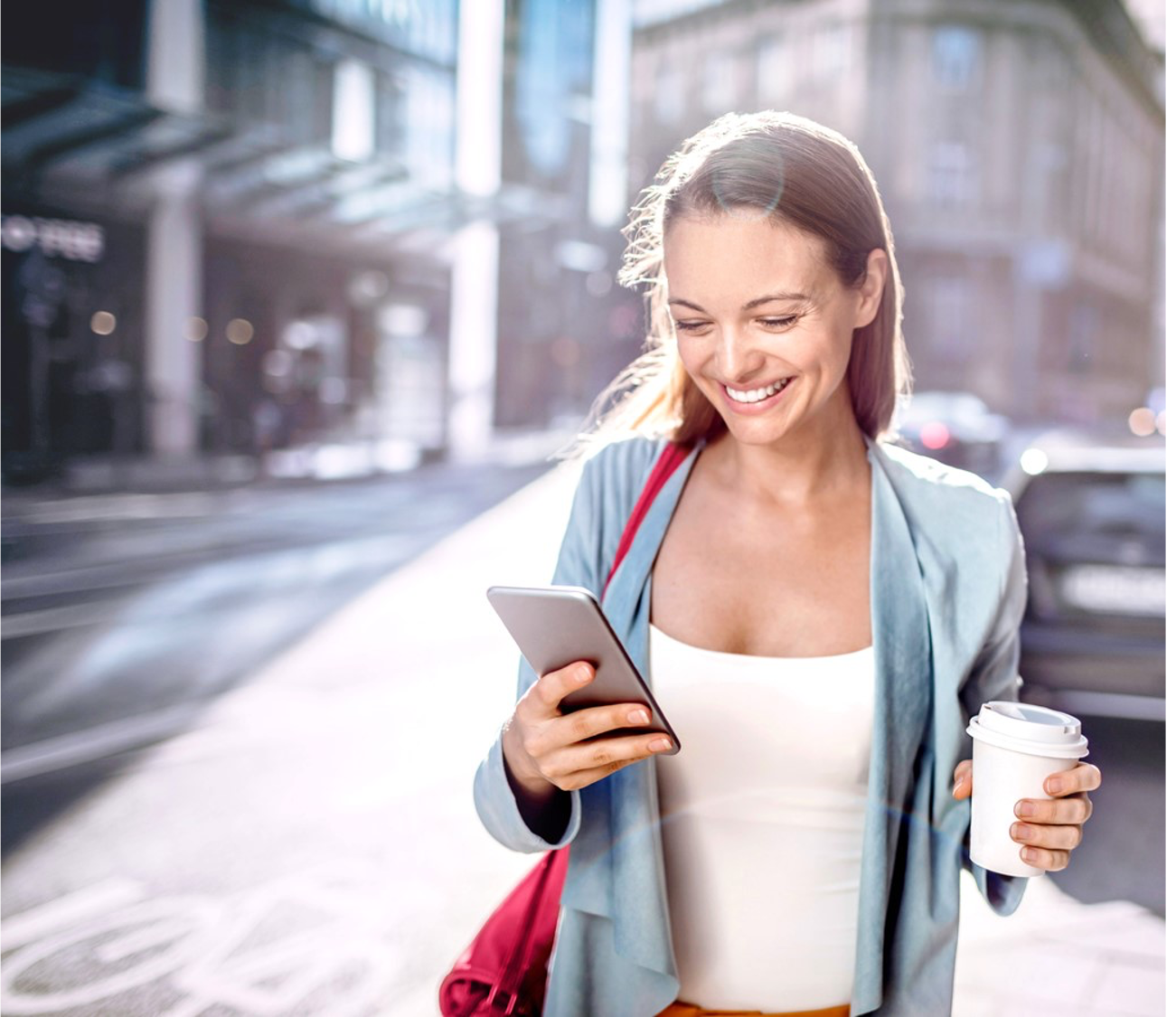 Frau; die einen Kaffeebecher und Handy in den Händen hält.