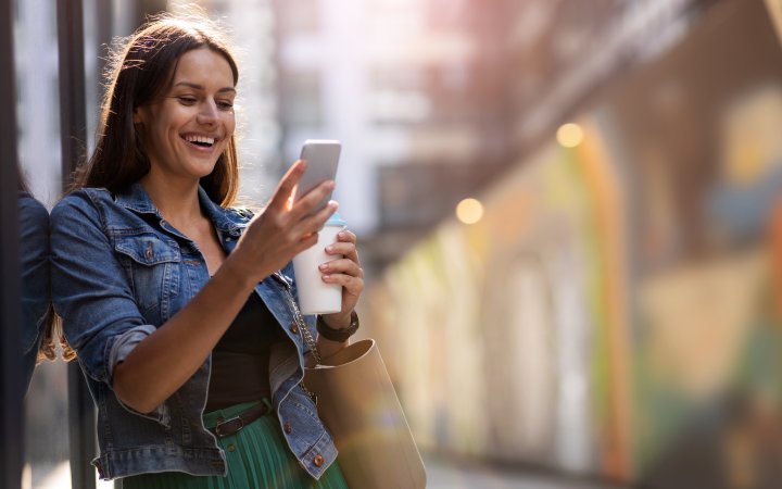 Lächelnde Frau hält ein Smartphone.