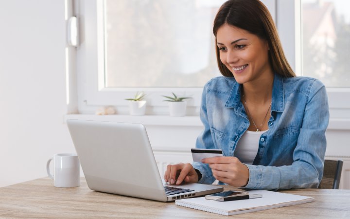 Lächelnde Frau sitzend vor einem Laptop.