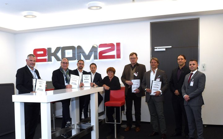 Mehrere Personen präsentieren ein Dokument in Räumlichkeiten der ekom21.
