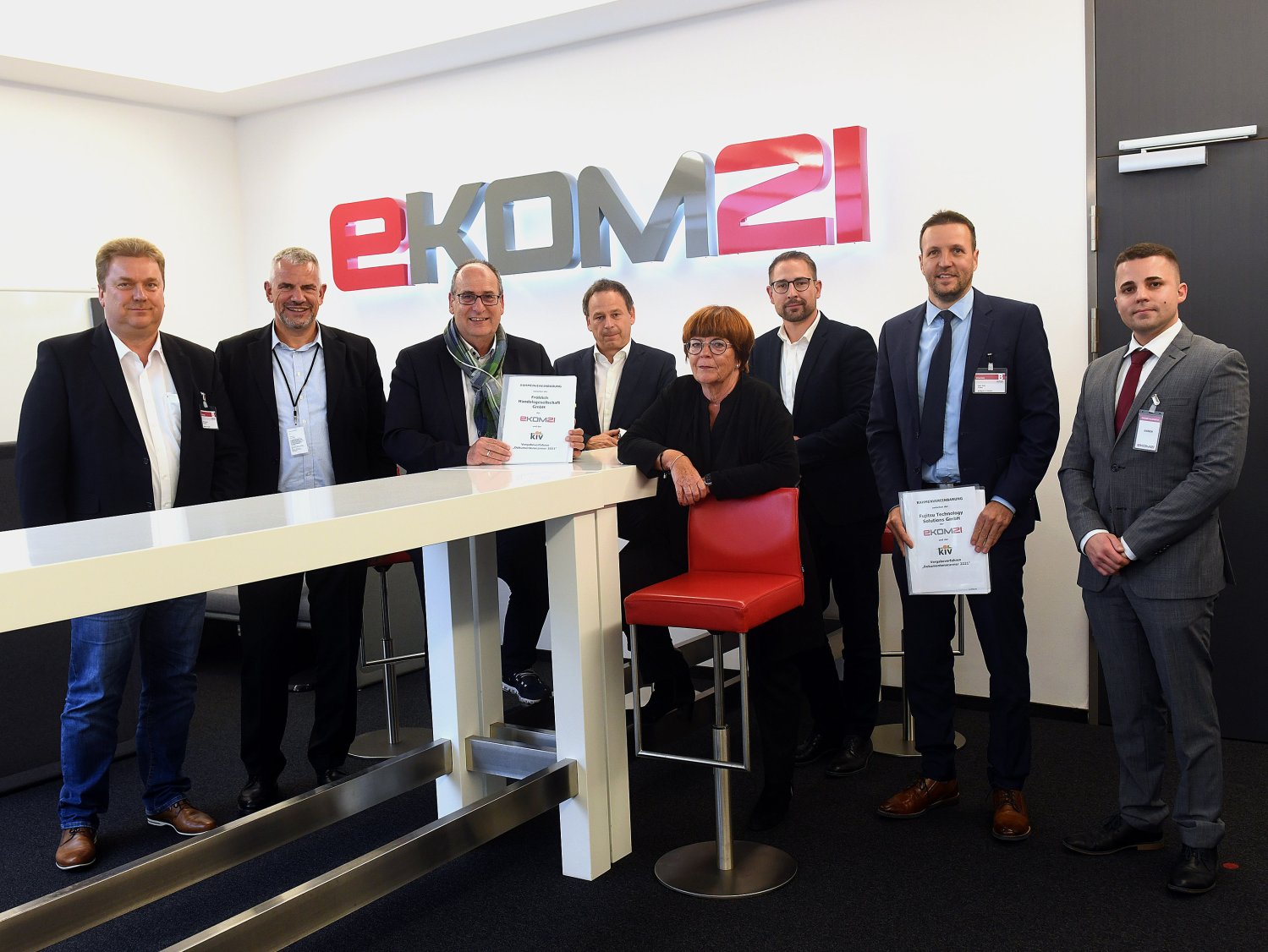 Mehrere Personen präsentieren ein Dokument in Räumlichkeiten der ekom21.
