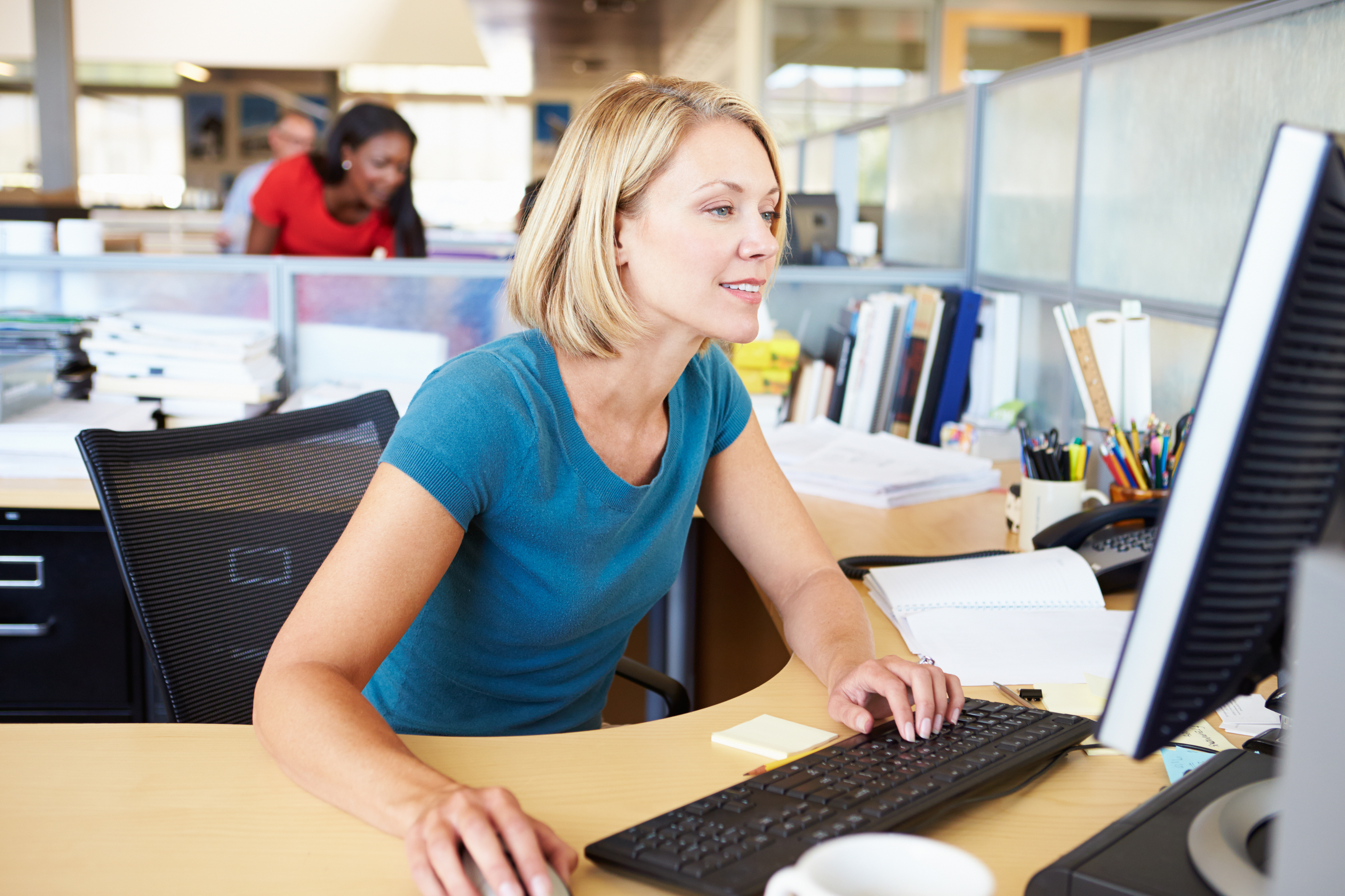 Frau sitzend am Computer im Büro.
