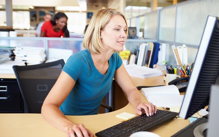 Frau sitzend am Computer im Büro.