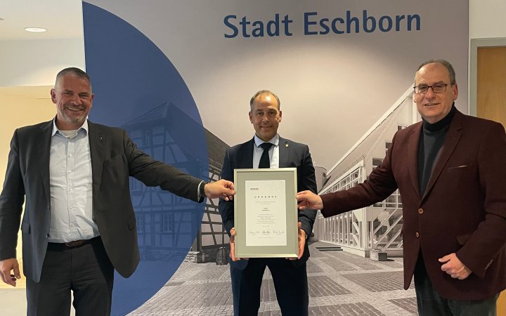 Betram Huke und Matthias Drexelius überreichen Adnan Shaikh eine Urkunde.