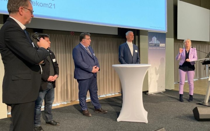 Mehrere; sich unterhaltende Personen während einer Podiumsdiskussion.