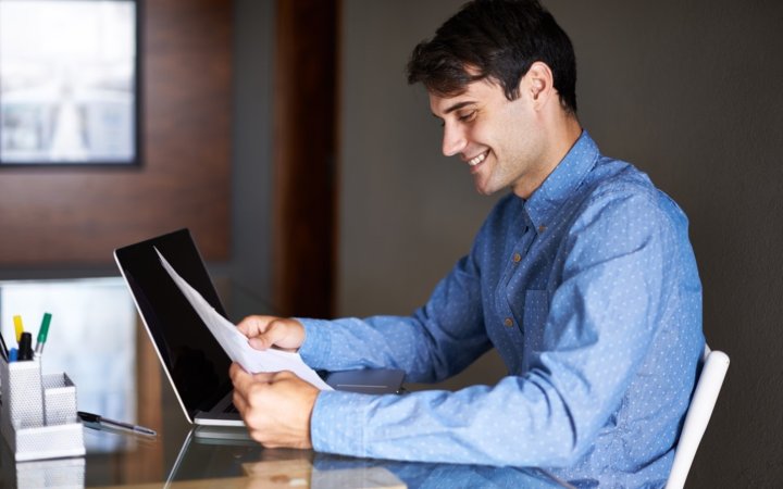 Mann an Büroarbeitsplatz betrachtet ein Tablet.