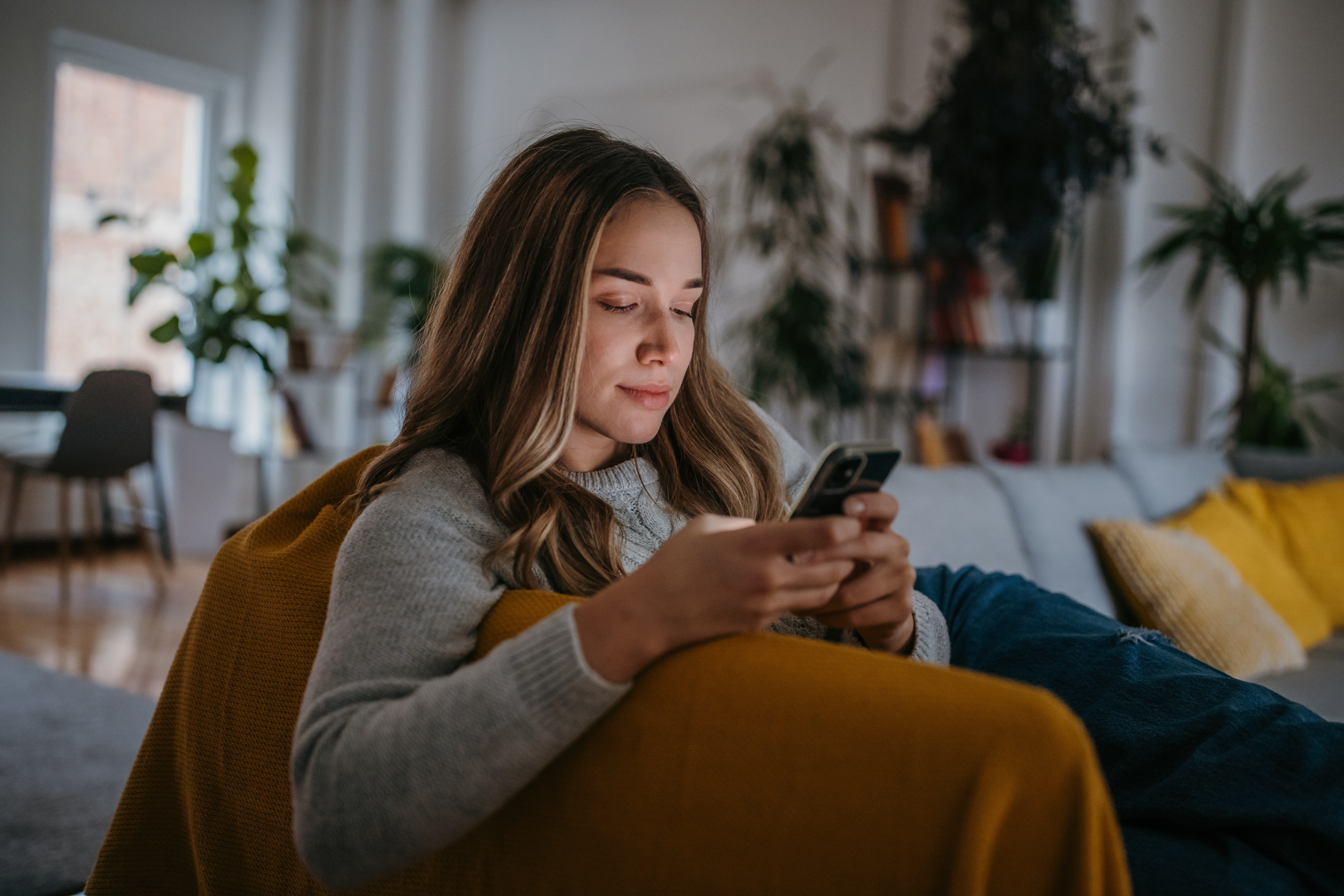 Frau sitzend; blickt in ihr Handy.