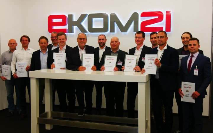 Gruppe von Personen in Räumlichkeiten der ekom21 präsentieren unterzeichnete Verträge.