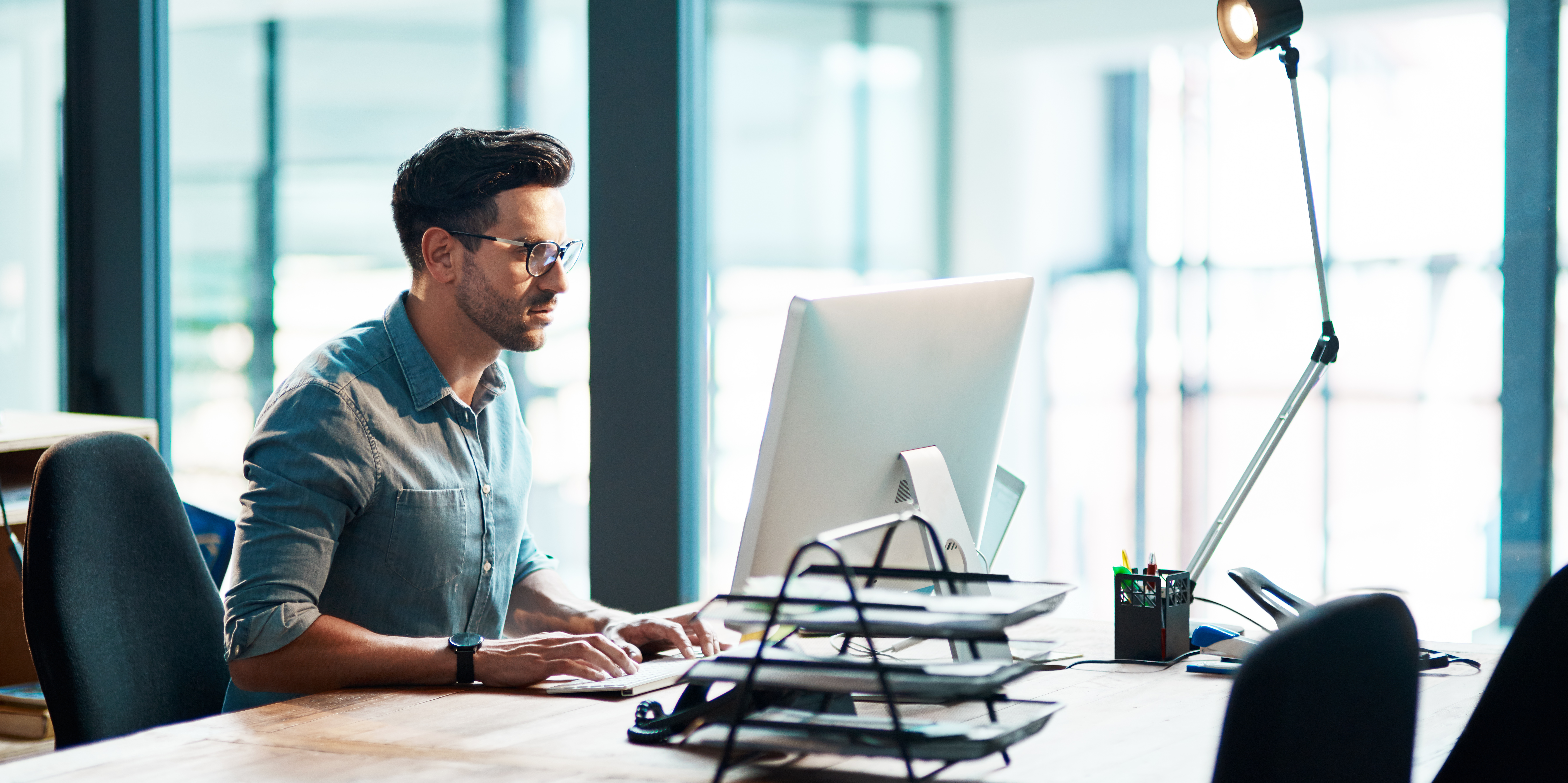 Mann; sitzend am Büroarbeitsplatz.