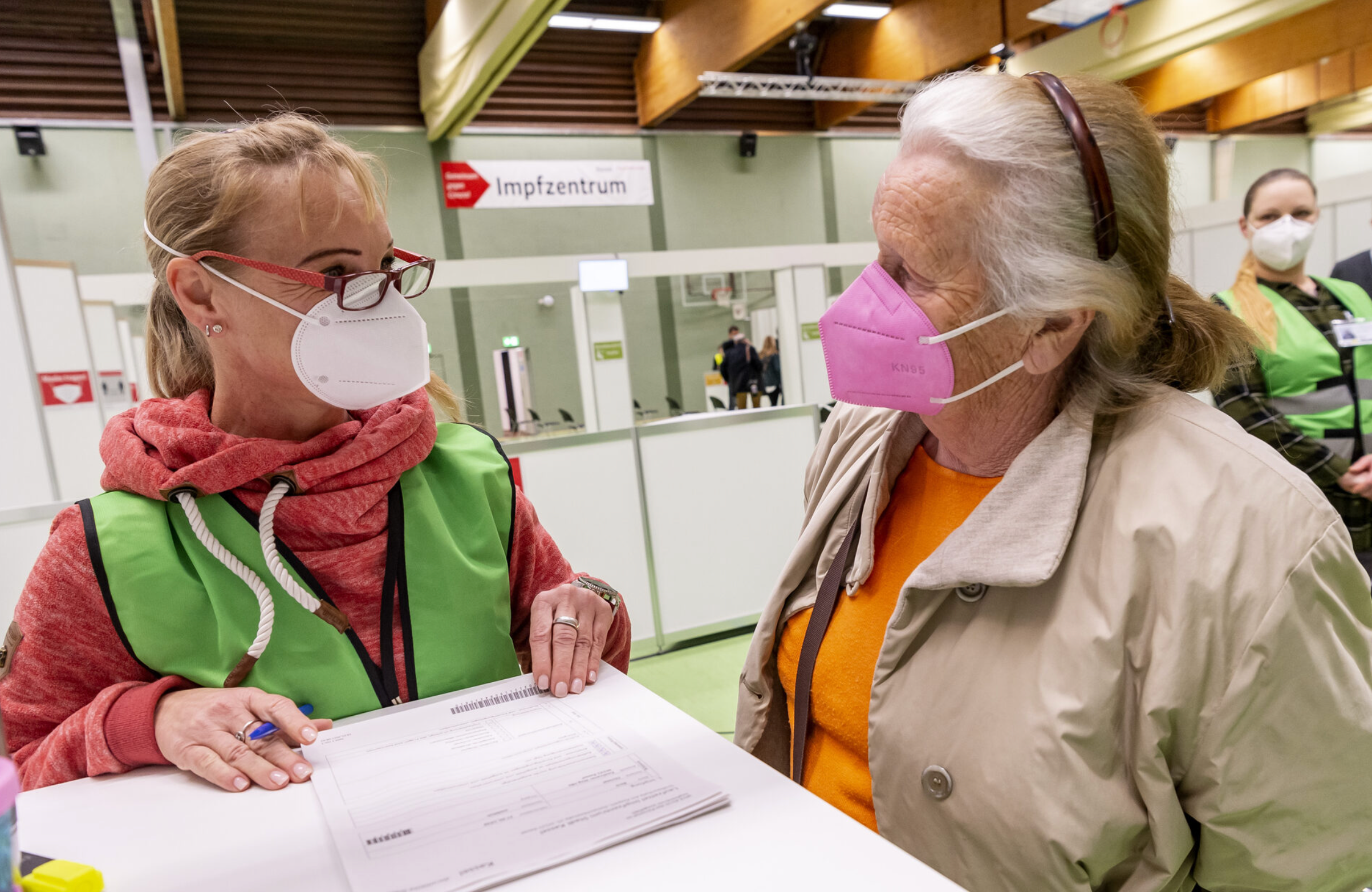 Zwei Personen mit Corona-Schutzmasken in einem Gespräch.