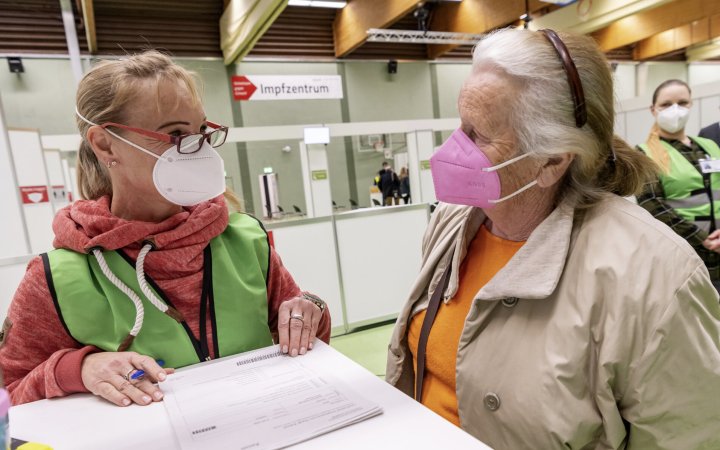 Zwei Personen mit Corona-Schutzmasken in einem Gespräch.