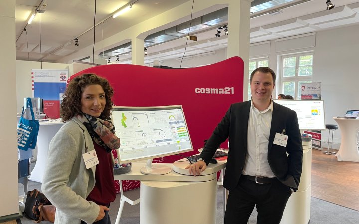 Zwei Personen an einem Stand von cosma 21.