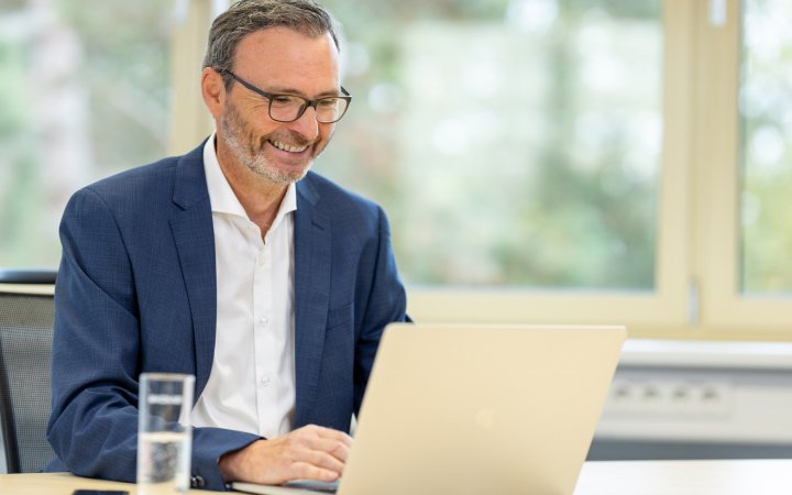 Sitzende Person vor einem Laptop.