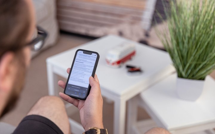 Junger Mann auf Couch schaut auf Smartphone. 