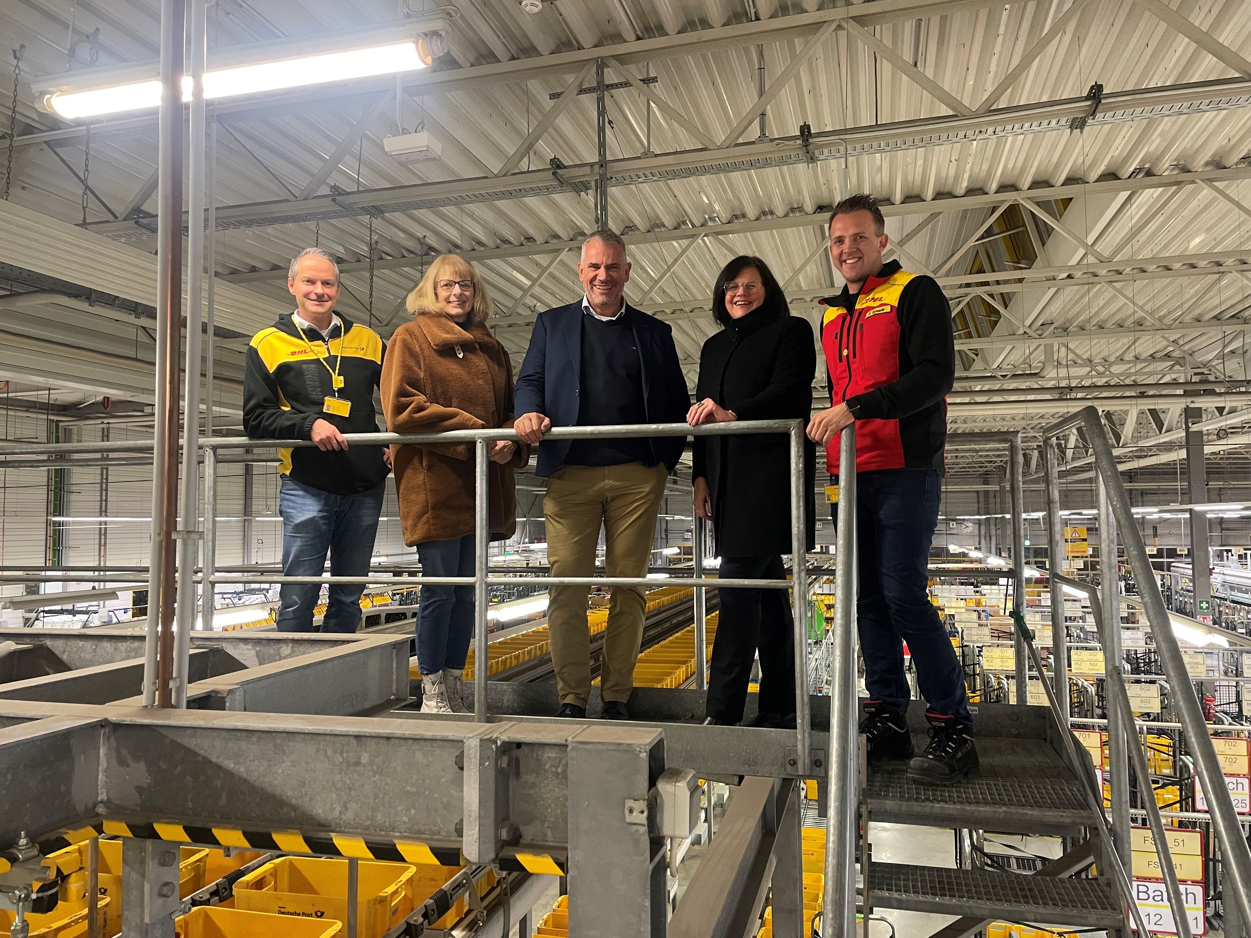 Matthias Drexelius mit vier Personen in einem Logistikgebäude der deutschen Post
