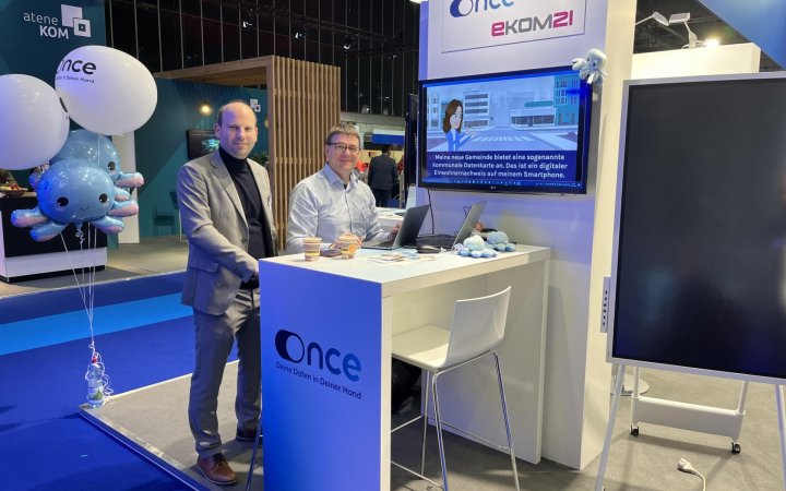 Zwei Personen an einem Stand der ekom21 während einer messeartigen Veranstaltung. 