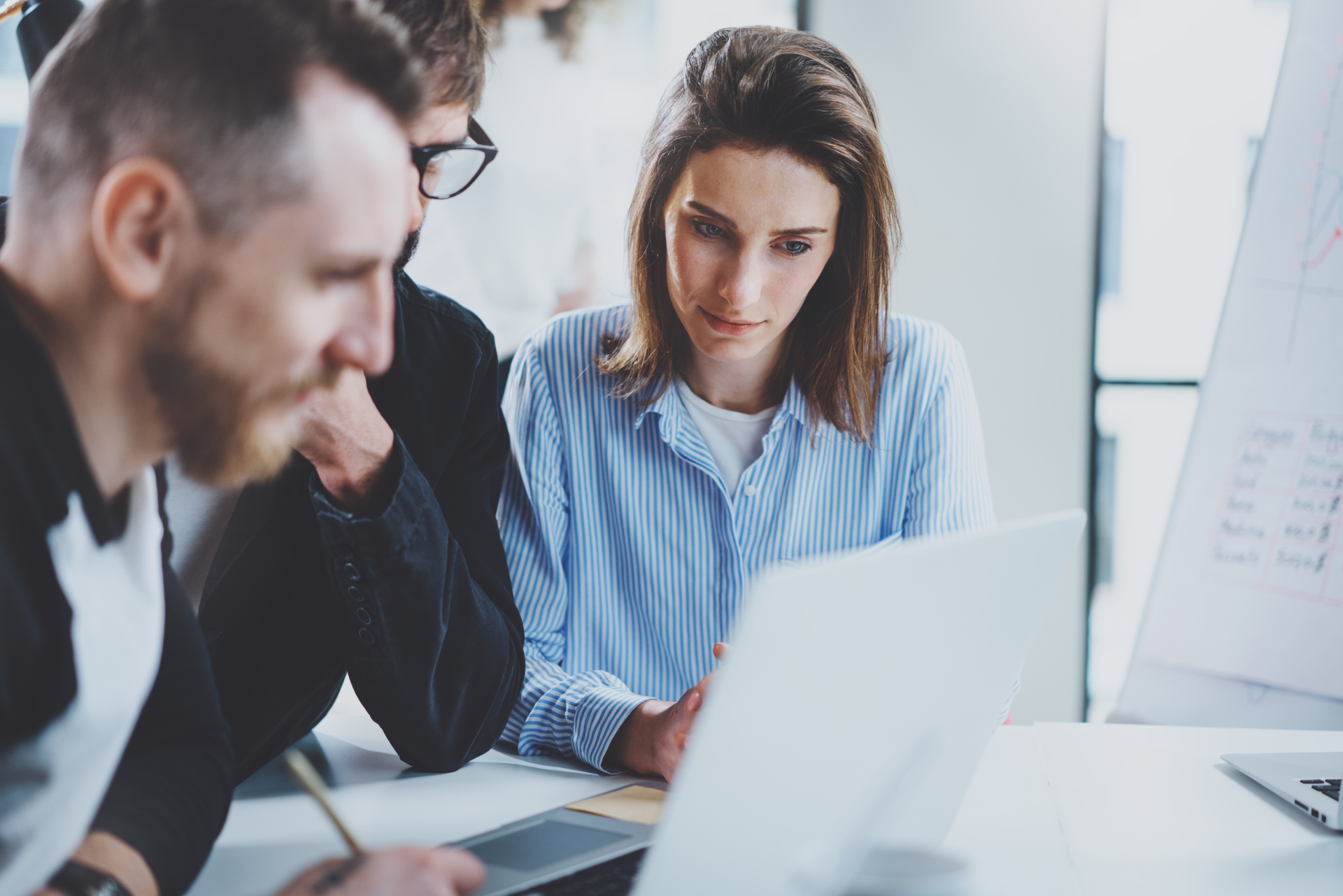 Three coworkers at working process.Young woman working together with colleague at modern office.Teamwork concept. Blurred background.Horizontal. Three coworkers at working process.Young woman working together with colleague at modern office.Teamwork concept. Blurred background.Horizontal.