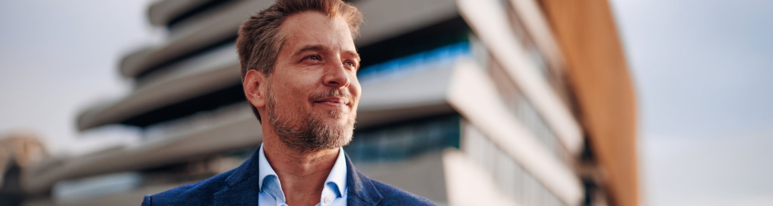 Confident businessman looking up at modern building with hope and ambition