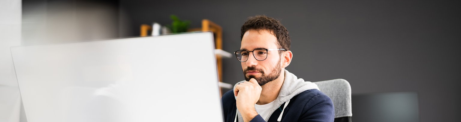 Sitzender Mann vor einem Computer.