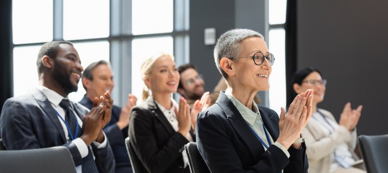 joyful multicultural business people applauding during seminar, blurred background Mehrere Geschäftsmänner und -frauen applaudieren in Seminarraum