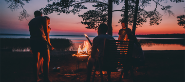 Eine Gruppe Menschen bei Dämmerung an einem Lagerfeuer