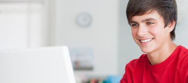 junger Mann in rotem T-Shirt vor einem Laptop