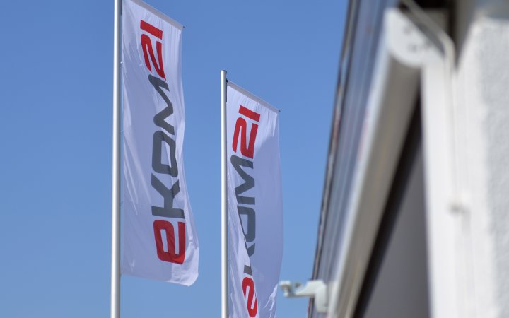 Zwei Fahnenmäste mit Fahnen; auf den Fahnen das Logo der ekom21
